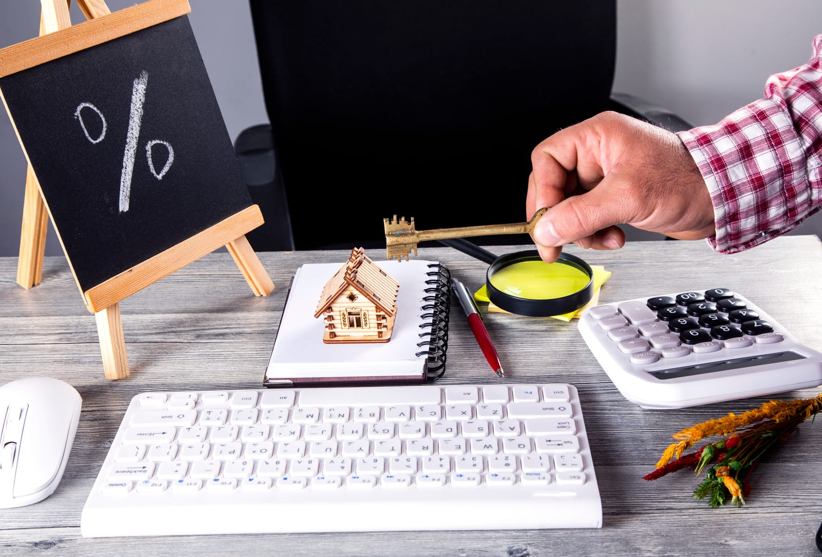 Desk with calculator, house model, key, notebook, and keyboard, symbolizing home planning, finance, and property services.